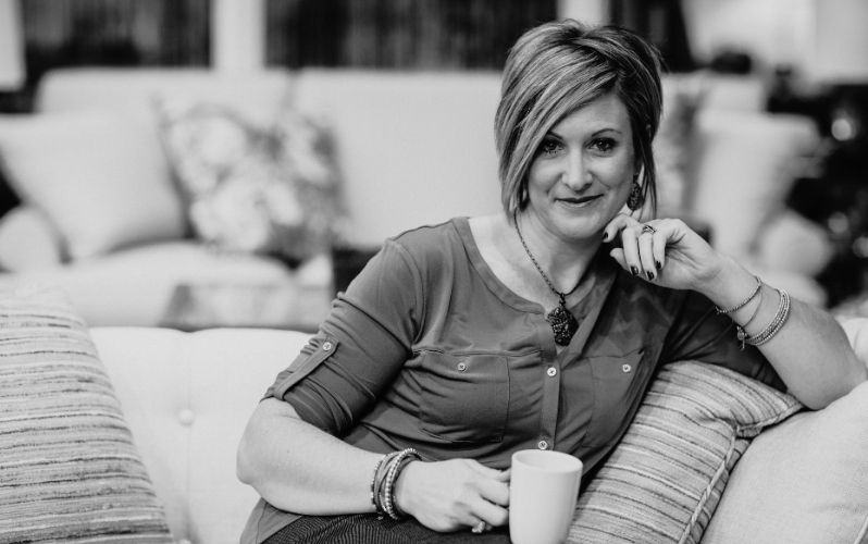 Woman sitting on the couch with a cup of coffee looking at the camera