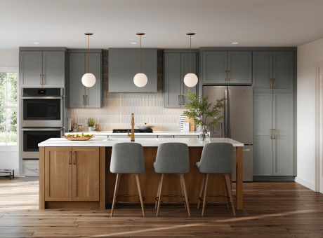 A modern kitchen with grey cabinets, wooden island, countertop, pendant lights, and appliances.