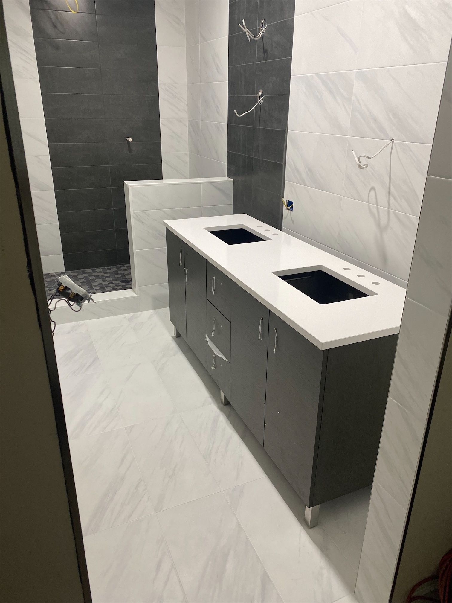 Black vanity with quartz countertops and quartz tiling in a bathroom
